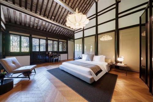 a bedroom with a bed and a chair and a chandelier at 芯宿-上海陶家宅 in Shanghai