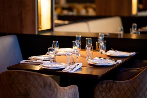 a wooden table with glasses and plates and napkins at Apart-Hotel Ariš Kopaonik in Kopaonik