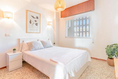 a white bedroom with a white bed and a window at Apartamento Mormor in Las Lagunas Mijas