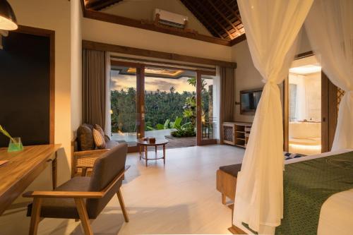 a bedroom with a bed and a living room at Sanggraloka Ubud in Ubud