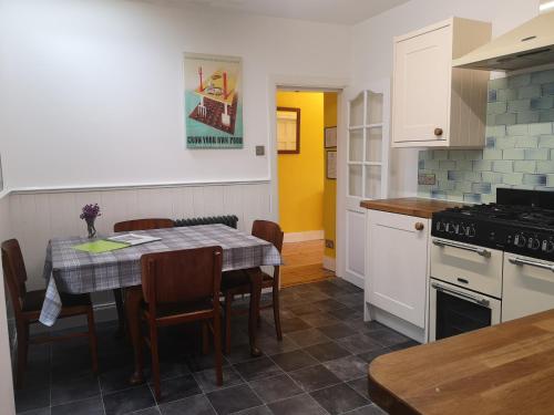 a kitchen with a table and chairs and a kitchen with yellow at Friars Shott Cottage in Inverness