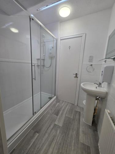 a white bathroom with a shower and a sink at Beach Hotel Torbay B&B in Paignton