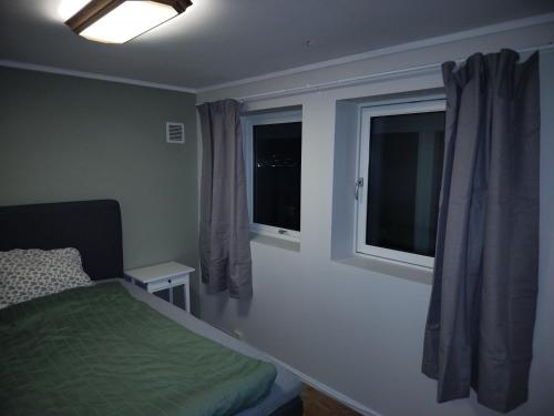 a small bedroom with a bed and two windows at Prekestolen, Pulpit Rock in Strand