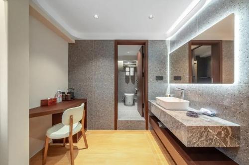 La salle de bains est pourvue d'un lavabo et d'un comptoir avec une chaise. dans l'établissement 三间堂百年徽商俞家 婺源月亮湾店, à Wuyuan