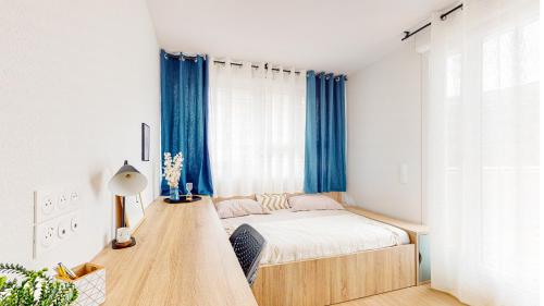 a small bedroom with a bed and blue curtains at Sweetly I-Art Gradignan - Bordeaux Sud in Gradignan