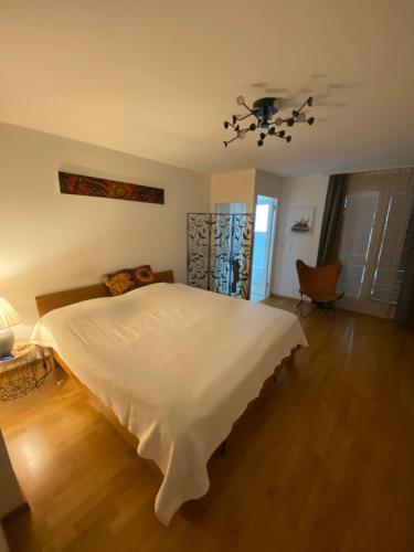 a bedroom with a large white bed and a chair at Stylish Room and private bathroom in lakefront apartment in Zug
