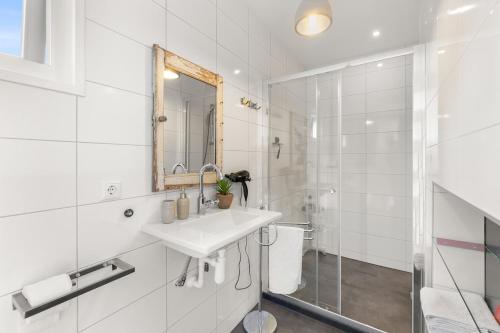 a white bathroom with a sink and a shower at NEW! Vakantiehuis Grijpskerke met airco en houtkachel - 2 personen in Grijpskerke