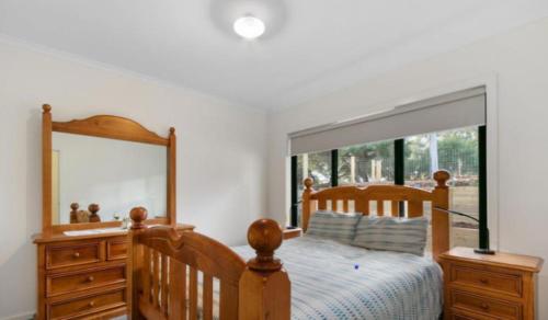 a bedroom with a wooden bed and a large mirror at Goodlett Corner- oasis of peace in Loch Sport