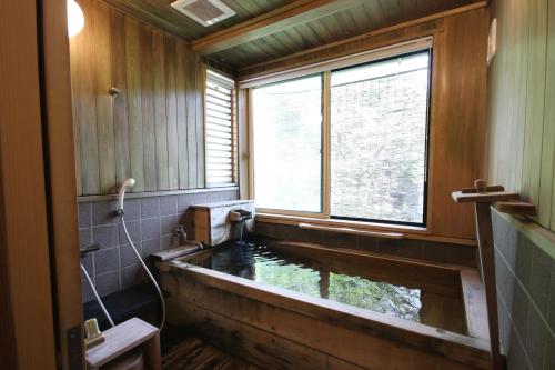 a bathroom with a bath tub with a window at 塵表閣本店 in Yamanouchi