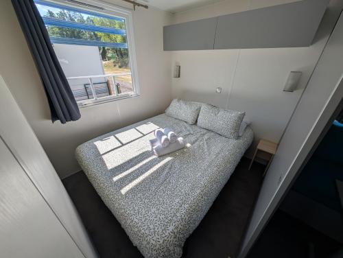 a small bed in a small room with a window at Camping BOSQUE DE G0RD0N in La Pola de Gordón