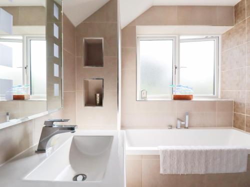 a bathroom with a tub and a sink and two windows at Seaspell Beach House in Padstow
