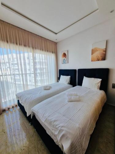 a bedroom with two beds and a large window at BenHost Appartement Casablanca Maarif in Casablanca