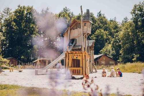 a playground with a wooden play structure in the sand at Veluwepark de Bosgraaf - Glamping in Lieren
