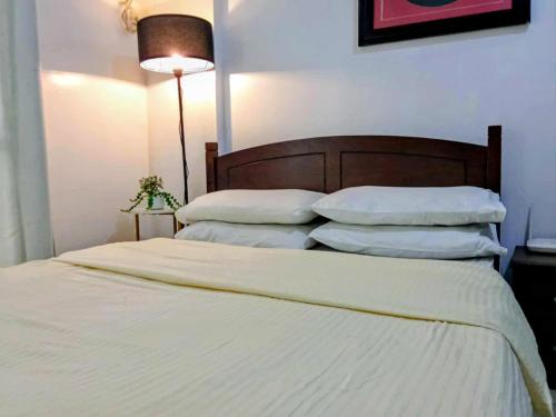 a bedroom with a bed with white sheets and pillows at The Redwoods SM Fairview by PreciousGem in Manila
