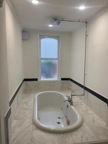 a white tub in a bathroom with a window at Pet Friendly 2 Bed Ground Floor Apartment in Addlestone with Free Driveway Parking in Addlestone