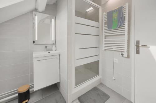 a white bathroom with a sink and a shower at Dentelle in Caudry