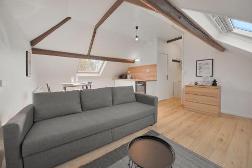 a living room with a gray couch and a kitchen at Dentelle in Caudry