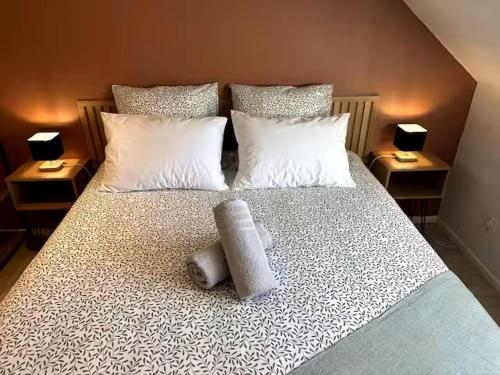 a bed with white pillows and two towels on it at Le cocon du Florival- Guebwiller in Guebwiller