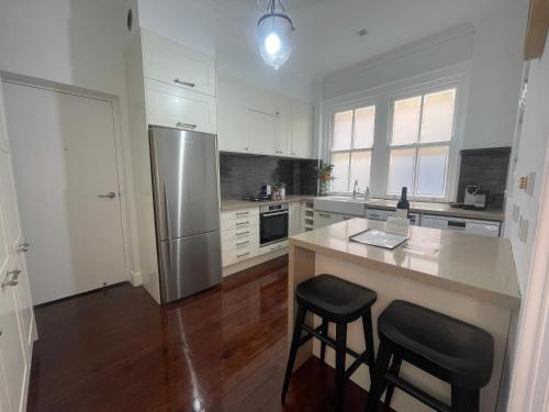 a kitchen with a stainless steel refrigerator and two bar stools at Luxury heritage Hideaway - close to CBD! in Sydney