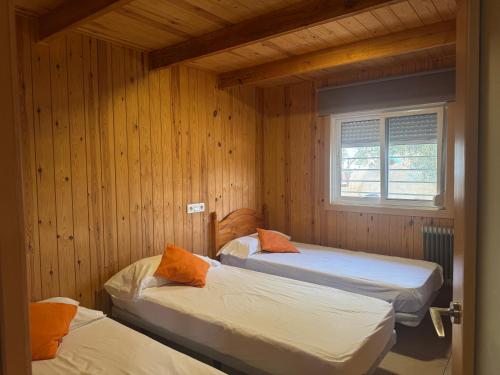 two beds in a room with wooden walls at Caseta De L'avi in Camarles