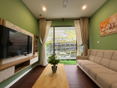 a living room with a couch and a large window at Cameron Palas Homestay in Brinchang