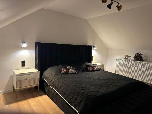 a bedroom with a black bed with two stuffed animals on it at Domek Nad Odrą in Krajnik Dolny