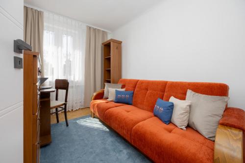 an orange couch with pillows in a living room at Spacious Apartment Close to Warsaw for 5 people by Noclegi Renters in Konstancin-Jeziorna