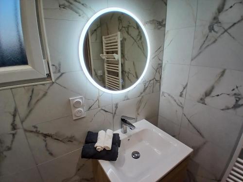 a white bathroom with a sink and a mirror at La pause enchantee in Villarcoin
