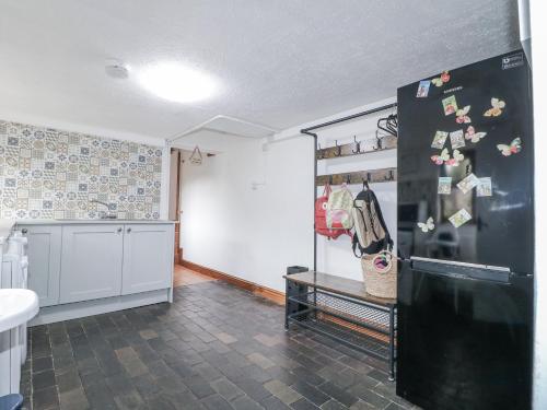 a kitchen with a black refrigerator with magnets on it at Yoxall Cottage in Alton