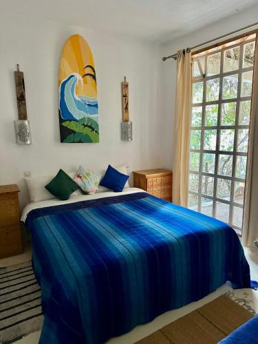 a bedroom with a bed with a surfboard on the wall at Cozy 1BR Bungalow with Kitchen in Eco Garden Nature Escape in Agadir