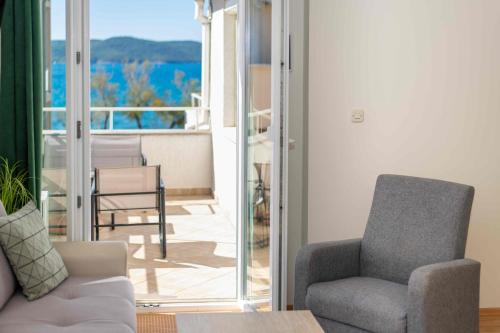 a living room with a couch and a chair and a balcony at Luxury Beach Apartment w Sunset Sea Views in Šibenik