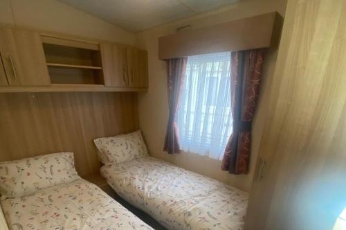 a small room with two beds and a window at 2 Bed Caravan-Sleeps 6-Pet Friendly in Warton