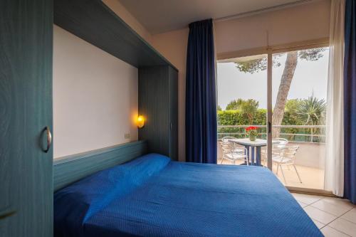 een slaapkamer met een blauw bed en een balkon bij Villaggio Turistico La Cecinella in Marina di Cecina