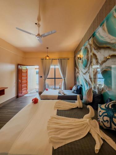 a bedroom with a large bed with a painting on the wall at Ari Stay Thoddoo in Thoddoo