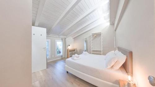 a white bedroom with a bed and a window at LE Home Soave - Locazione Turistica in Soave