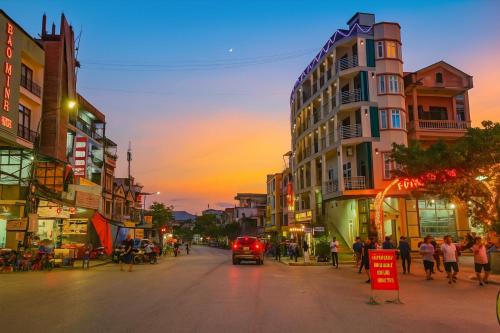 a city street at sunset with a car driving down the street at Thái Thịnh Hotel in Dồng Văn
