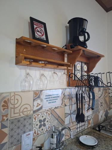 a kitchen counter with wine glasses and utensils at Chalés Metanóia in São Pedro da Serra