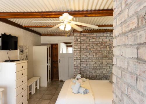 FraserburgにあるOu Klipskuur Self-Catering Accommodationのレンガの壁、天井ファン付きのベッドルーム1室