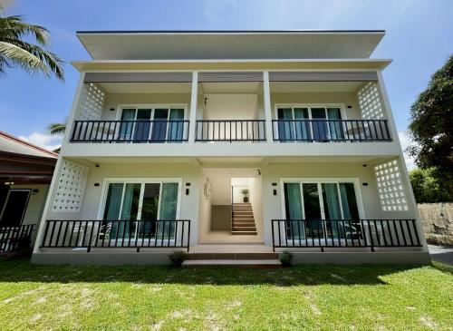 a large white house with a balcony at The Pinda House Bangtao in Bang Tao Beach