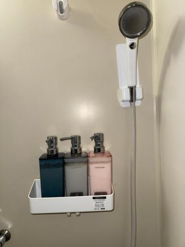 Un soporte de pared con tres botellas en una pared. en Uhome Akazu hostel, en Tokorozawa