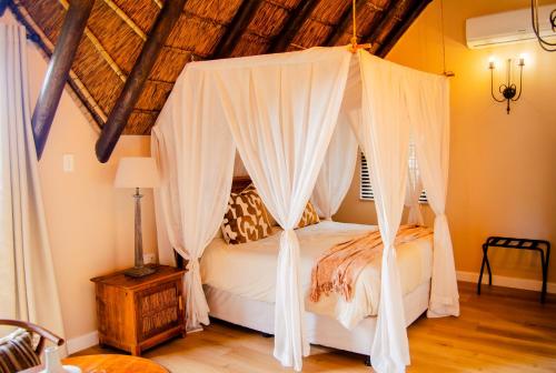 a bedroom with a canopy bed with white drapes at Ikhaya Safari Lodge in Cape Town