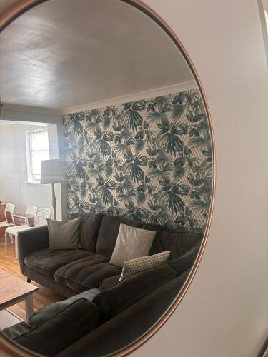 a mirror reflecting a couch in a living room at Stylish & Spacious 2 Storey, 3 Bed Apartment in Kent