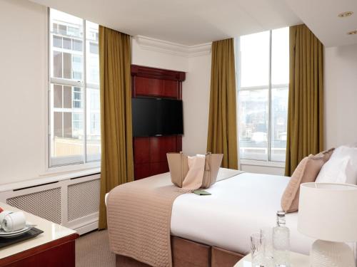 ein Hotelzimmer mit einem großen Bett und einem Fenster in der Unterkunft The Prime London Hotel in London