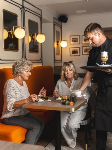 a man and woman sitting at a table with a plate of food at Villa Herkules - Adults Only in Świnoujście