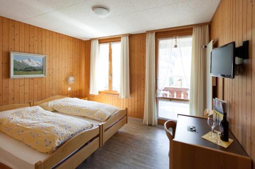 a bedroom with a bed and a tv on a wall at Hotel Edelweiss in Wengen