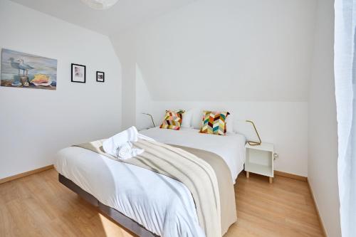 two beds in a room with white walls and wood floors at Le Quai Bleu - 200 m de la plage in Courseulles-sur-Mer