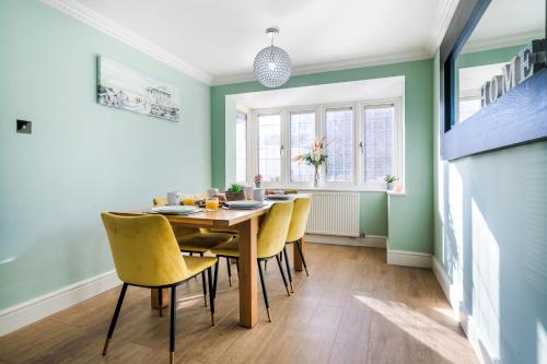 a dining room with a wooden table and yellow chairs at Halsey 4-Bed Premier Contractor Relocator Family Freeparking in Hemel Hempstead