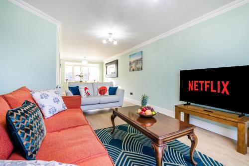 a living room with a red couch and a tv at Halsey 4-Bed Premier Contractor Relocator Family Freeparking in Hemel Hempstead
