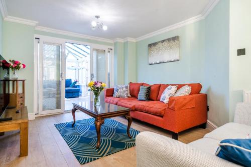 a living room with a red couch and a table at Halsey 4-Bed Premier Contractor Relocator Family Freeparking in Hemel Hempstead