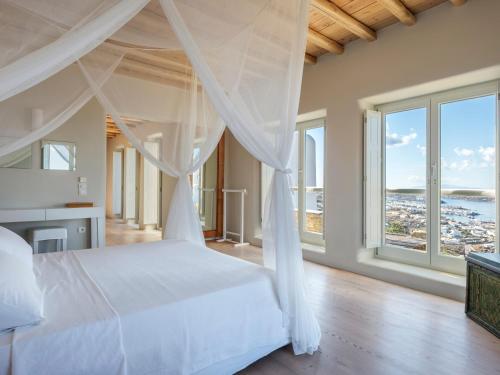 a bedroom with a white bed with a view of the ocean at Villa Montessito Mykonos in Tourlos